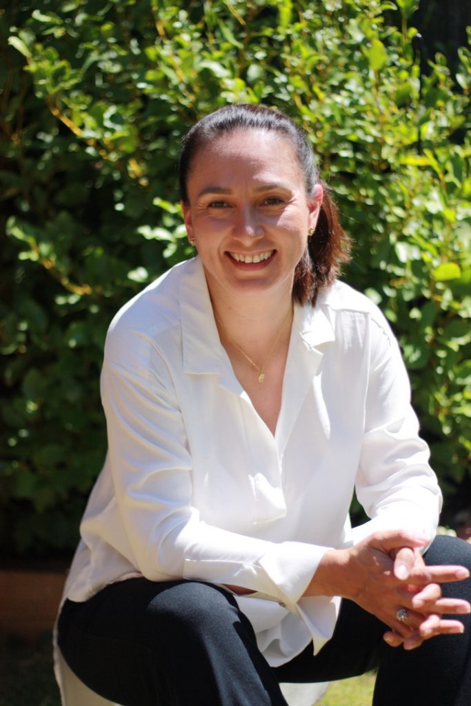 Juliana sitting by some trees.